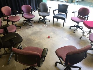 empty office chairs in circle with a coke bottle in the middle on the ground